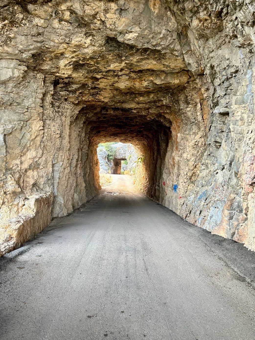 Kayaya oyulmuş bir yol tüneli; taşın karanlığından geçen yolun ucunda gün ışığı görünüyor.